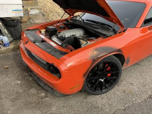 An orange Challenger with the front bumper off